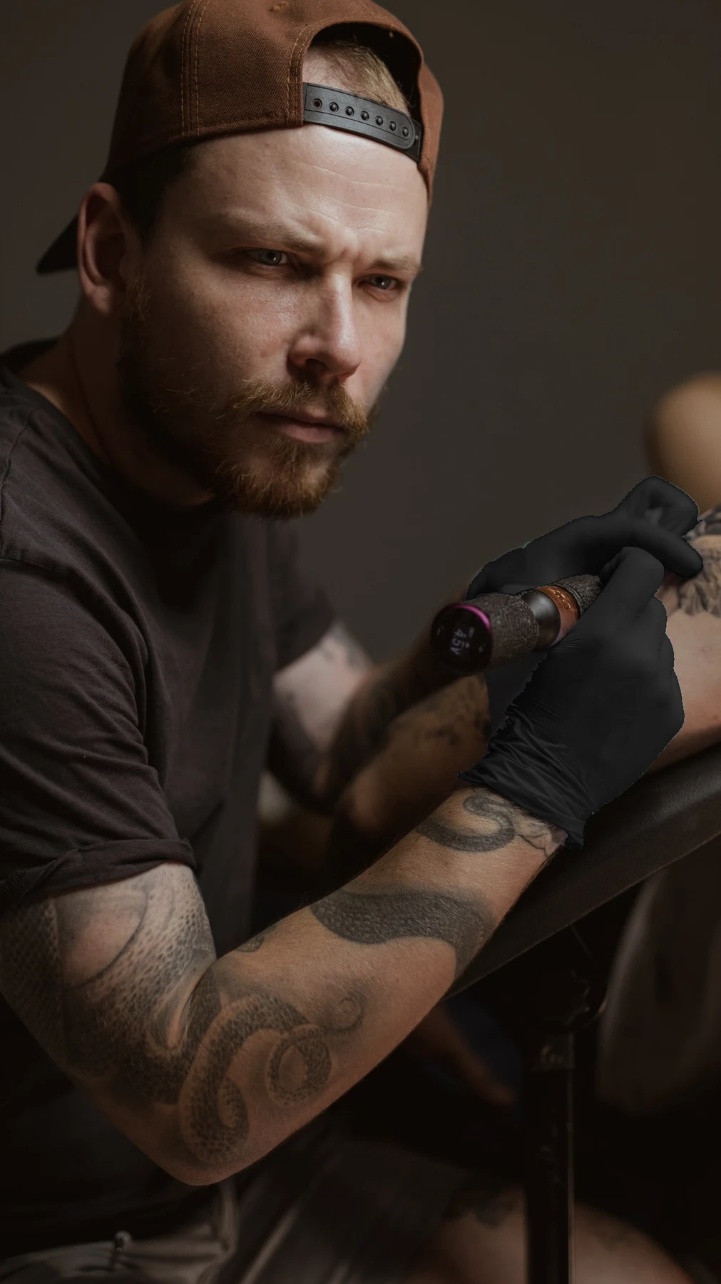 Ivan holding his tattoo machine, wearing black gloves
